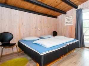 ロモ・キルケビーにあるThree-Bedroom Holiday home in Rømø 50の木製の壁のドミトリールームのベッド1台分です。