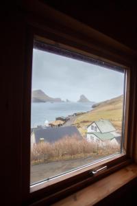 a window with a view of the ocean and houses at Idyllic Vacation Home with a Breathtaking View in Bøur