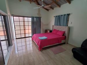 a bedroom with a pink bed in a room with windows at Oasis de Paz 3 in Jarabacoa