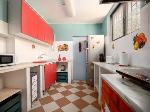 cocina con armarios rojos y nevera en HAVANA VINTAGE Alojamentos Quartos, en Santiago do Cacém