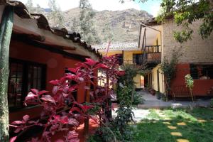 a courtyard of a house with red plants at B&B Sun Gate in Ollantaytambo