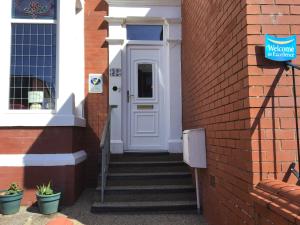 a white door on a brick building with stairs at The Woodleigh family hotel in Blackpool