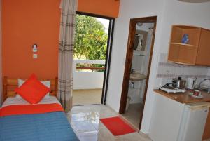 カルダメナにあるStergia Apartmentsの小さなベッドルーム(ベッド1台付)、バルコニーへのドアが備わります。