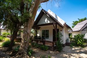 una pequeña casa blanca con un porche y un árbol en Southern Lanta Resort - SHA Extra Plus, en Ko Lanta