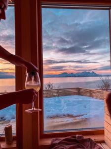 una persona che tiene un bicchiere di vino davanti a una finestra di Lyngen Alps Panorama a Russelv