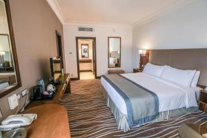 a hotel room with a large bed and a desk at Copthorne Downtown by Millennium in Abu Dhabi