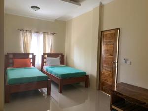 1 dormitorio con 2 camas, ventana y mesa en Diver's Cafe Amed, en Amed