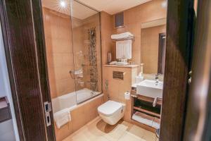 a bathroom with a toilet and a sink at Copthorne Downtown by Millennium in Abu Dhabi