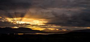 a sunset over a body of water with mountains at Aurora Borealis Observatory in Silsand