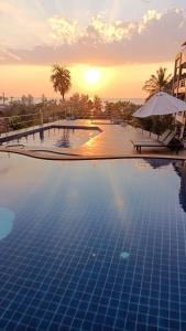 a large swimming pool with a sunset in the background at White Flower Lanta in Ko Lanta