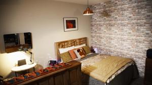 1 dormitorio con cama y pared de ladrillo en La Tannerie - BedinShop, en Romans-sur-Isère