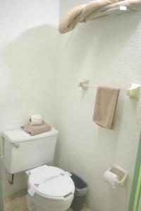 a white bathroom with a toilet and towels at Hotel Plaza Independencia in Villahermosa