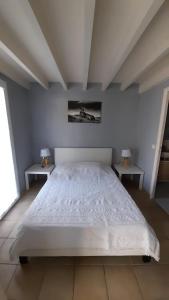 a bedroom with a white bed and two tables at Appartement SOULAC SUR MER À 500 m de la plage N 4 in Soulac-sur-Mer