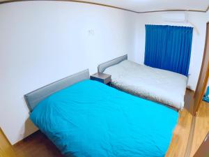 a small bedroom with a bed with blue sheets at SKYE HOME in Tokyo