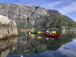 a group of people in kayaks on a lake with a mountain at Adventure hotel & GuestHouse Eidfjord NEW in Eidfjord