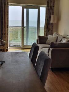 a living room with a table and a view of the ocean at Harbour Beach Apartment in Pevensey
