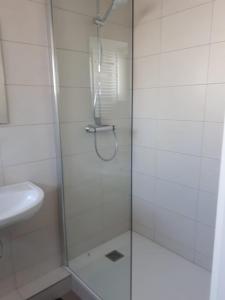 una ducha con una puerta de cristal junto a un lavabo en Manege volmolen, en Maaseik