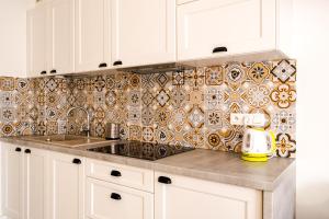 a kitchen with a sink and a tile wall at Apartamenty Homole in Szczawnica