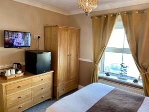 1 dormitorio con cama y vestidor con TV en Sunny Bank Guest House, en Tenby