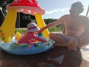 a man sitting next to a baby in an inflatable at LA HAUTE FORGE - B&B in Thoiré-sur-Dinan