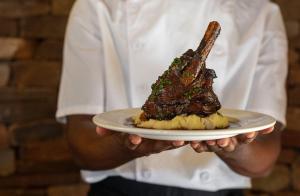 a chef holding a plate with a piece of meat at Mount Ceder in Cederberg