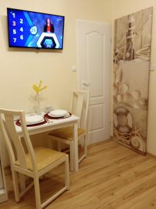 a dining room with a table and a tv on the wall at Apartament CURIE - studio in Międzyzdroje