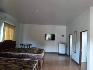 a room with two beds and a tv on the wall at Kaengkachan Lake Hill in Kaeng Krachan