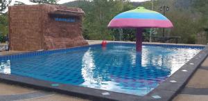 a swimming pool with an umbrella in the water at Kaengkachan Lake Hill in Kaeng Krachan
