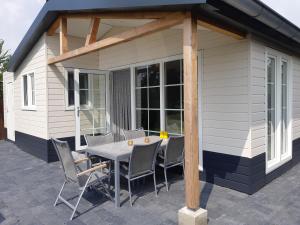 een patio met een tafel en stoelen voor een huis bij Nieuwe Beachbungalow aan IJsselmeer 39 24 four seasons in Lemmer