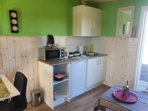 eine kleine Küche mit grünen Wänden und weißen Schränken in der Unterkunft Feriehytten Hønsehuset in Løkken