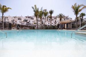 une grande piscine avec des palmiers et des bâtiments dans l'établissement Jardines de la Mata Boutique Beach, à Mojácar