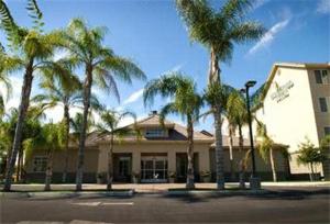 a building with palm trees in front of a street at Homewood Suites Bakersfield in Bakersfield