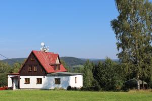 a white house with a red roof in a field at Holiday Home Jizerka in Nova Ves nad Nisou