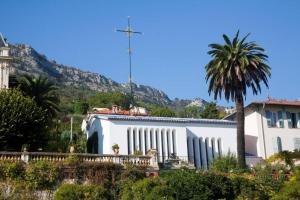 a church with a palm tree in front of a mountain at Charmant 2 pièces + terrasse entouré de verdure in Vence