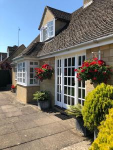 a house with white windows and red flowers on it at Cornerways B&B in Chipping Campden