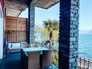 patio con tavolo, sedie e acqua di Apartments Posta al Lago a Ronco sopra Ascona