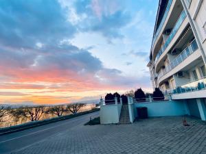 a building on a street with a sunset in the background at Aqua Blue Lakeview Apartment Ohrid in Peštani