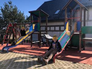 a child sitting on a slide at a playground at Willa i Domki Primore in Władysławowo