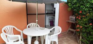 een witte tafel en stoelen en een parasol op een patio bij Karina Estudio in Praia do Forte