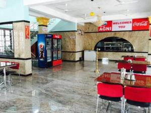 a restaurant with a soda machine and red chairs at Hotel Agni in Krishnagiri