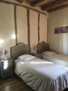 two beds in a room with wooden floors and beams at "La Maison de Villars" au coeur de la nature in Pressac
