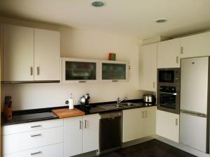 a kitchen with white cabinets and a sink and a refrigerator at Barranha Beach House in Aguçadoura