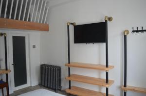 a flat screen tv on a wall with wooden shelves at Grooms House in Hebden Bridge