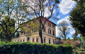 a large yellow house with red windows and trees at Villa Nardi - Residenza D'Epoca in Florence