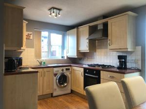 a kitchen with wooden cabinets and a washer and dryer at 2 The Mews in Winsford
