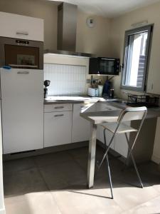 Una cocina con un refrigerador blanco y una mesa. en Studio T1BIS BORD DE PLAGE, en Saint-Lunaire