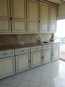 a kitchen with white cabinets and a white tile floor at Appartement rooftop vue mer in Antibes