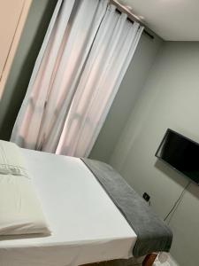 グアルジャにあるSanta Helena Pousadaのベッドルーム1室(ベッド1台付)、窓(テレビ付)