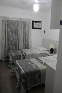 a room with two beds and a table with a lamp at Apartamento Costa Esmeralda in Bombinhas +10 photos