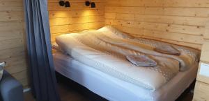 ein Bett in einem Holzzimmer mit zwei Schuhen darauf in der Unterkunft Hvammur 4 with private hot tub (Fagurgali) in Drangsnes